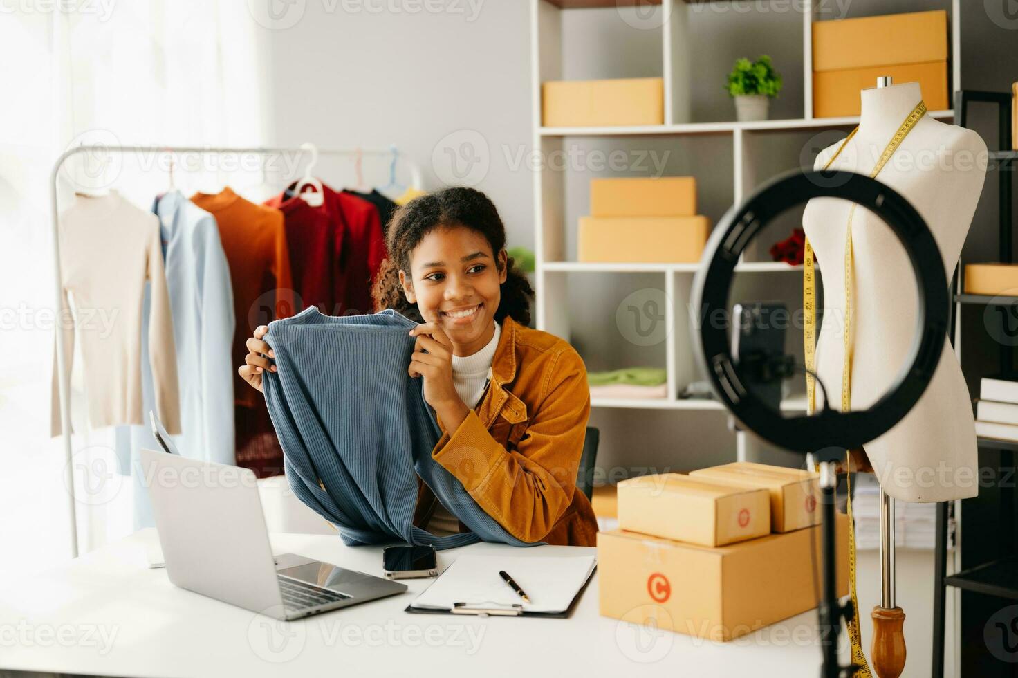 Fashion blogger concept, Young African women selling clothes on video streaming.Startup small business SME, using smartphone or tablet taking receive and checking photo