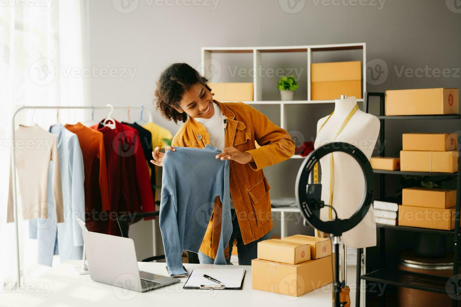 Fashion blogger concept, Young African women selling clothes on video streaming.Startup small business SME, using smartphone or tablet taking receive and checking photo