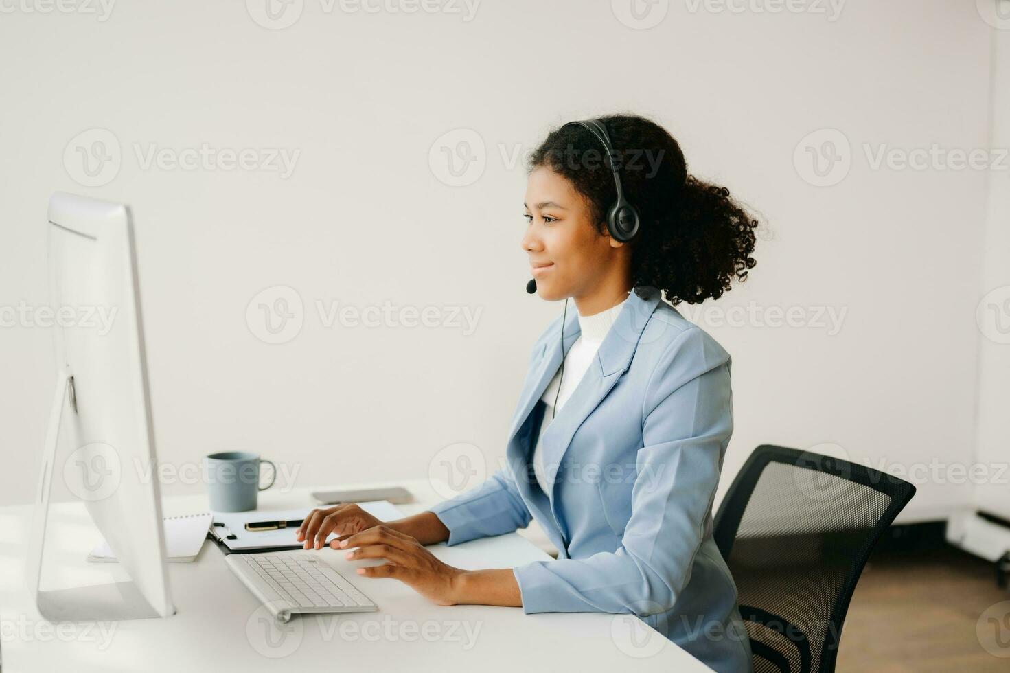 Serious call center operator in wireless headset talking with customer, woman in headphones with microphone consulting client on phone in customer support service in business center photo