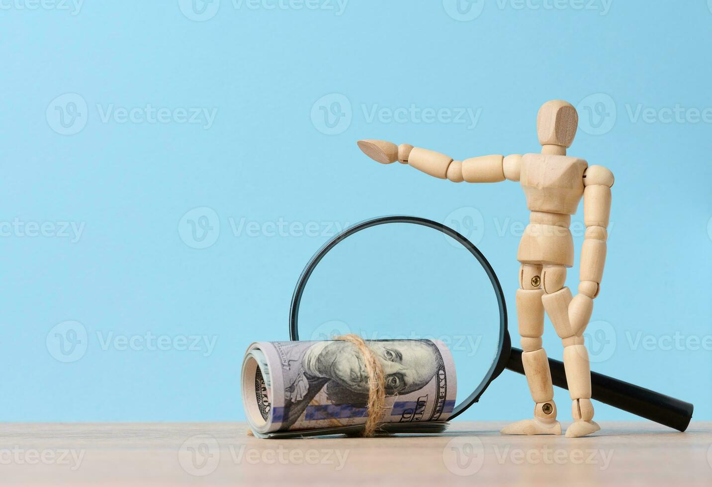 Wooden mannequin, magnifying glass and tied paper american dollars on a blue background, the concept of income growth photo