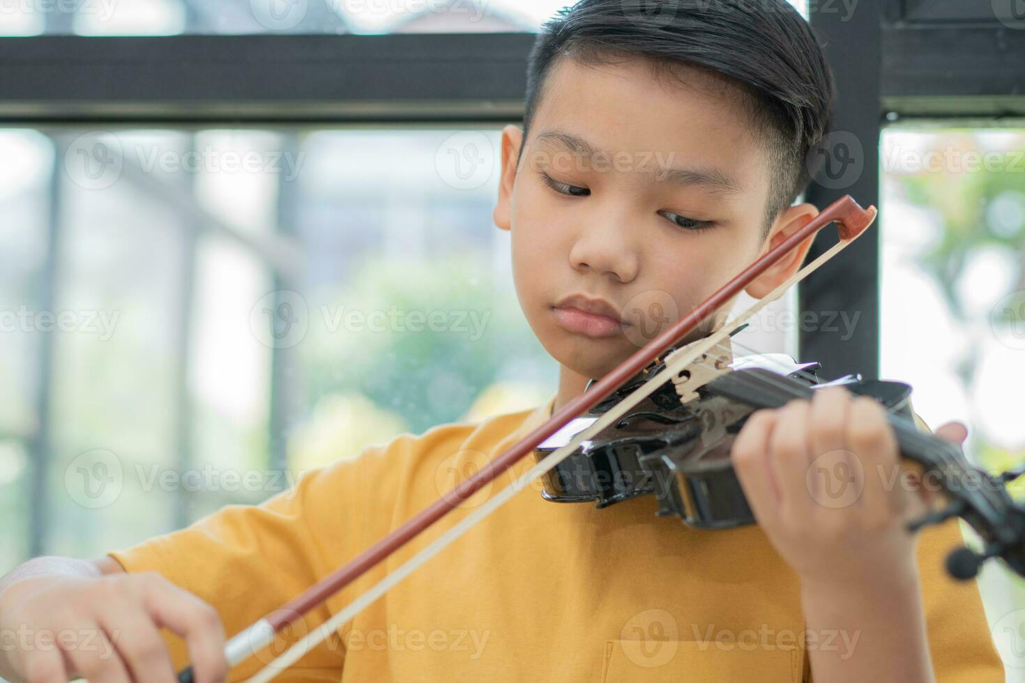 A Little Asian kid playing and practice violin musical string instrument against in home, Concept of Musical education, Inspiration, Teenager art school student. photo