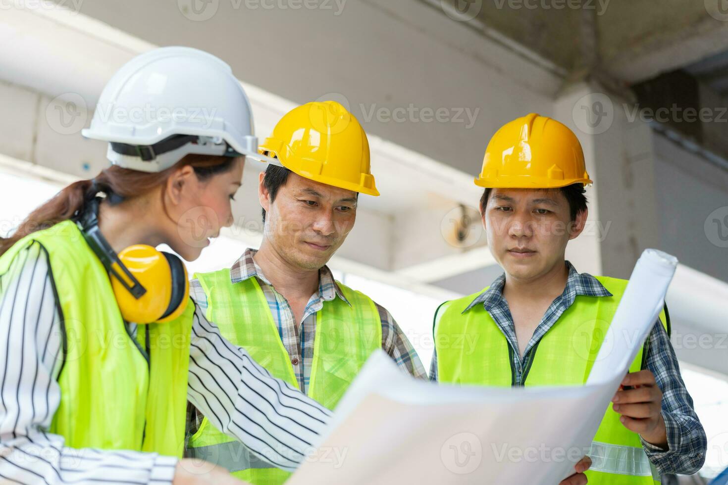 Asian engineer or Young Female Architect put on a helmet for safety and talk with a contractor on a construction building factory project, Concept of Teamwork, Leadership concept. photo