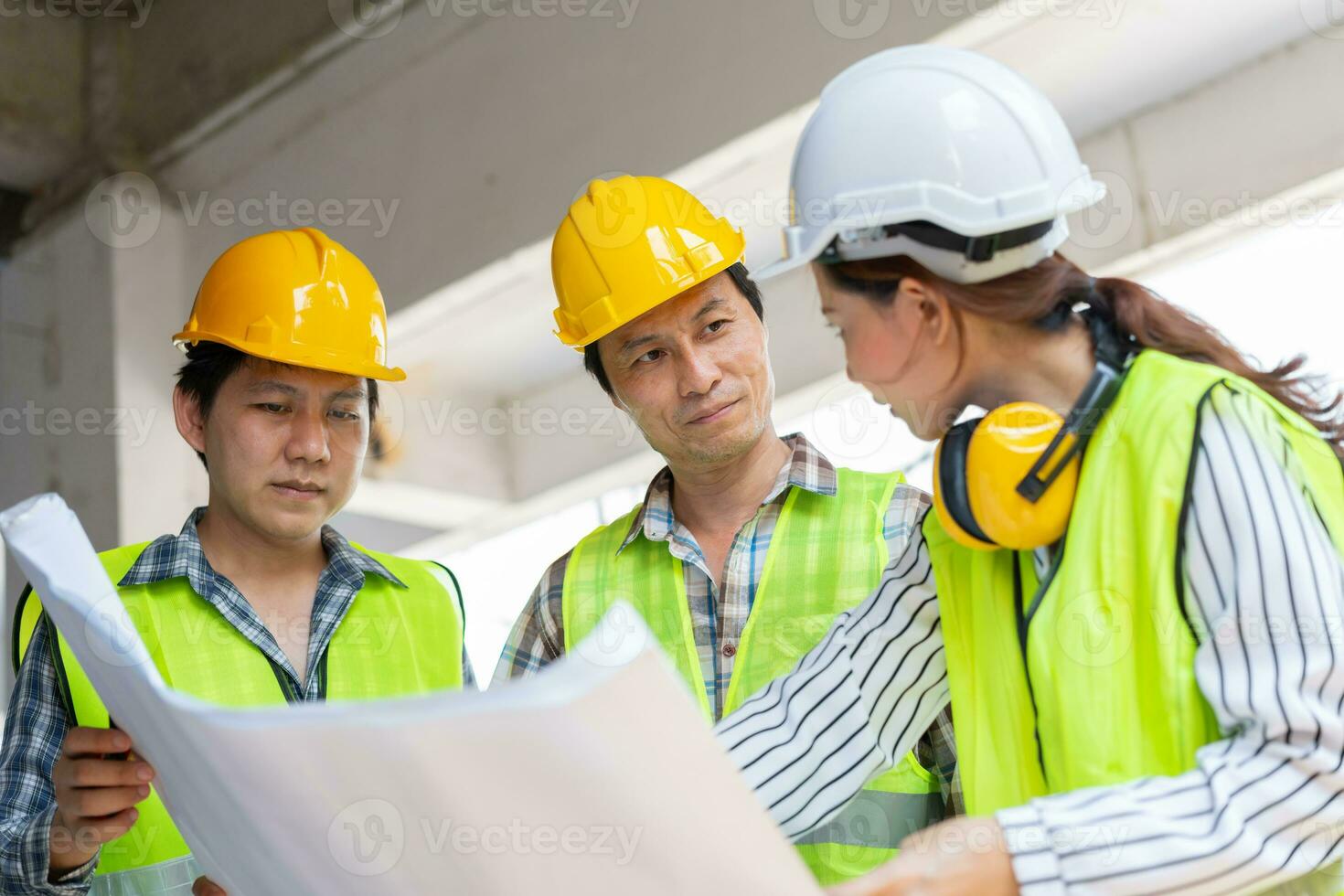 Asian engineer or Young Female Architect put on a helmet for safety and talk with a contractor on a construction building factory project, Concept of Teamwork, Leadership concept. photo