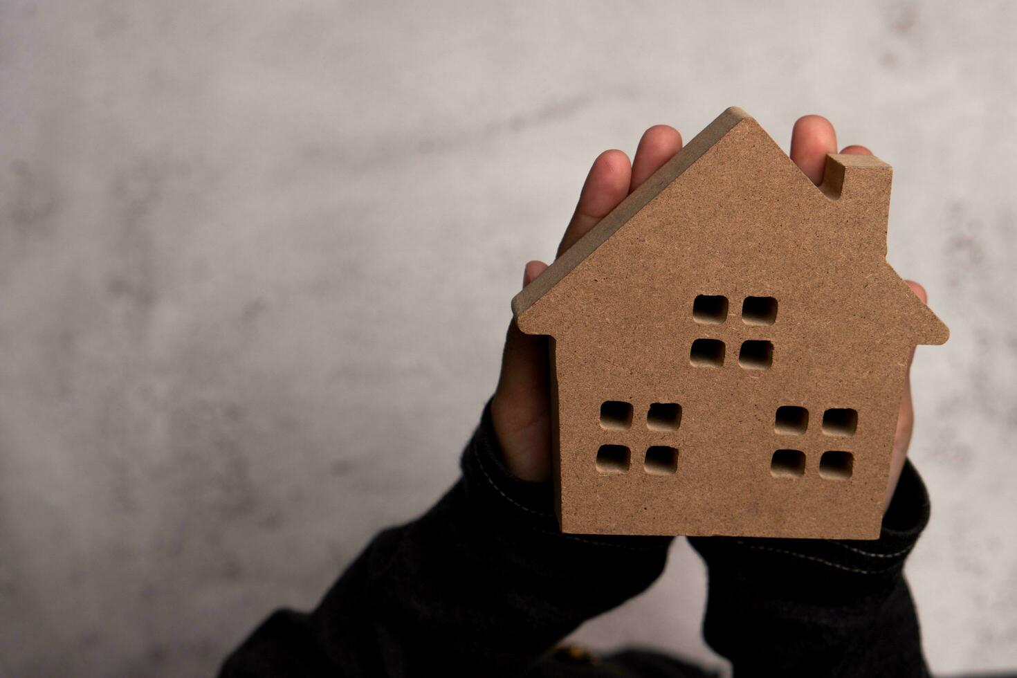 Child hand man holding a wooden model house. Concept of love family and security protection, Trust for construction and home renovation. photo