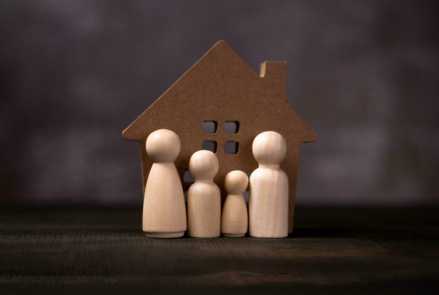 Wooden figures family standing in front of a wooden house. The concept of Protection and safety, Home Security, property insurance and house. photo