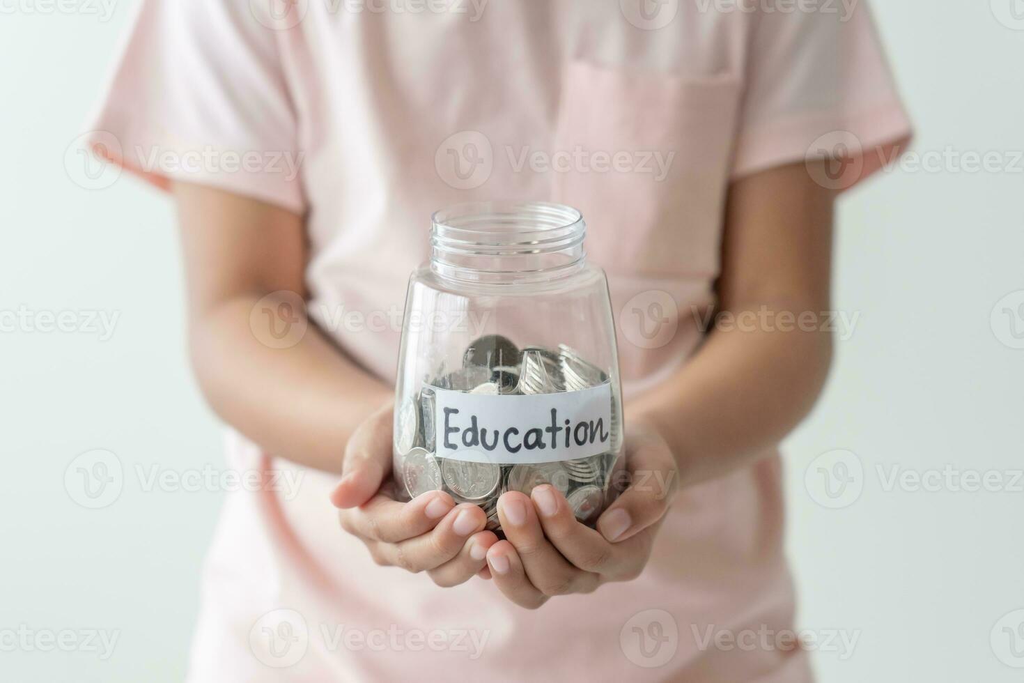 Kid holding her saving coins jar concept of savings money for future education school admission fee. Little daughter learn to save money. photo