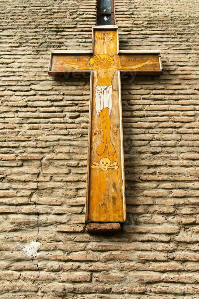 Orthodox Christian wooden cross on old brown brick in front of the church photo