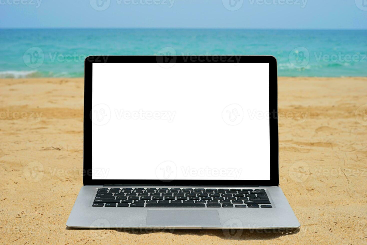 Close up of Laptop with blank screen for creative design on sand beach nearby blue sea background. Computer notebook with monitor clipping path for present landing page design mock up template photo