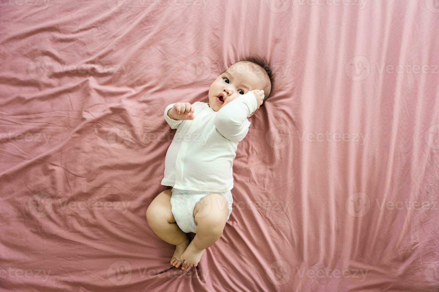 image of a newborn baby lying on a pink bed photo