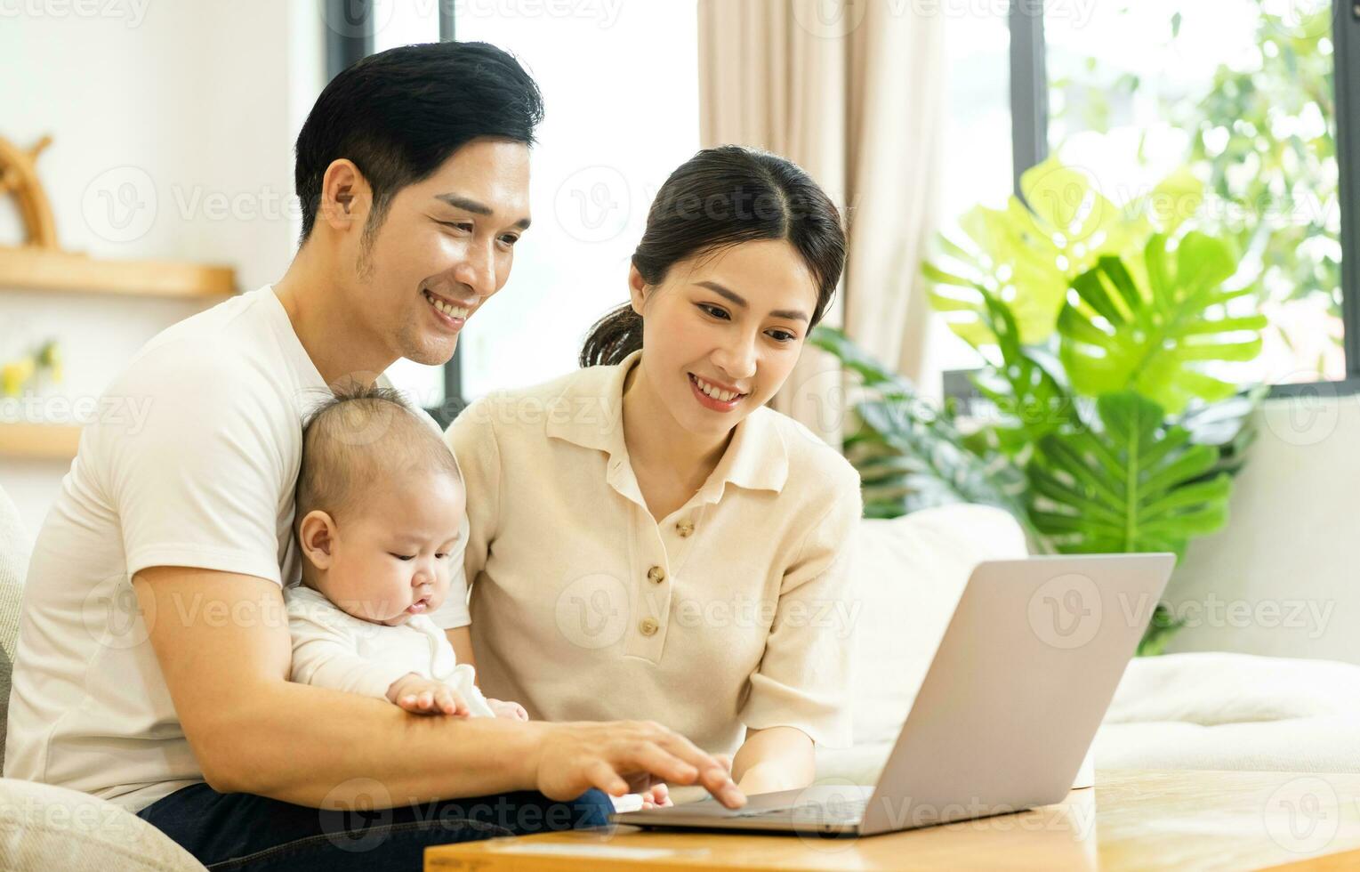 image of asian family with baby sitting on sofa using laptop photo