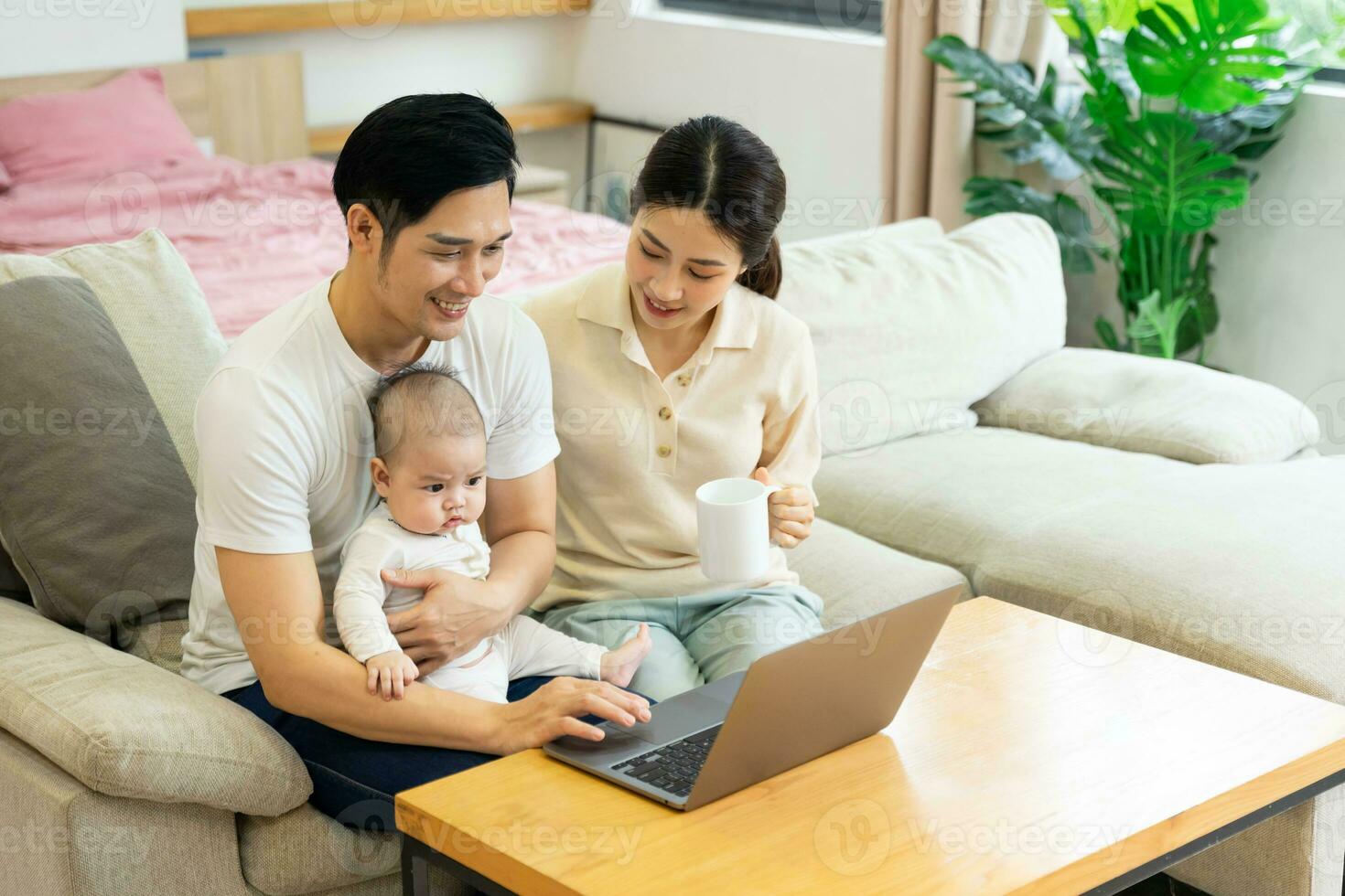 image of asian family with baby sitting on sofa using laptop photo