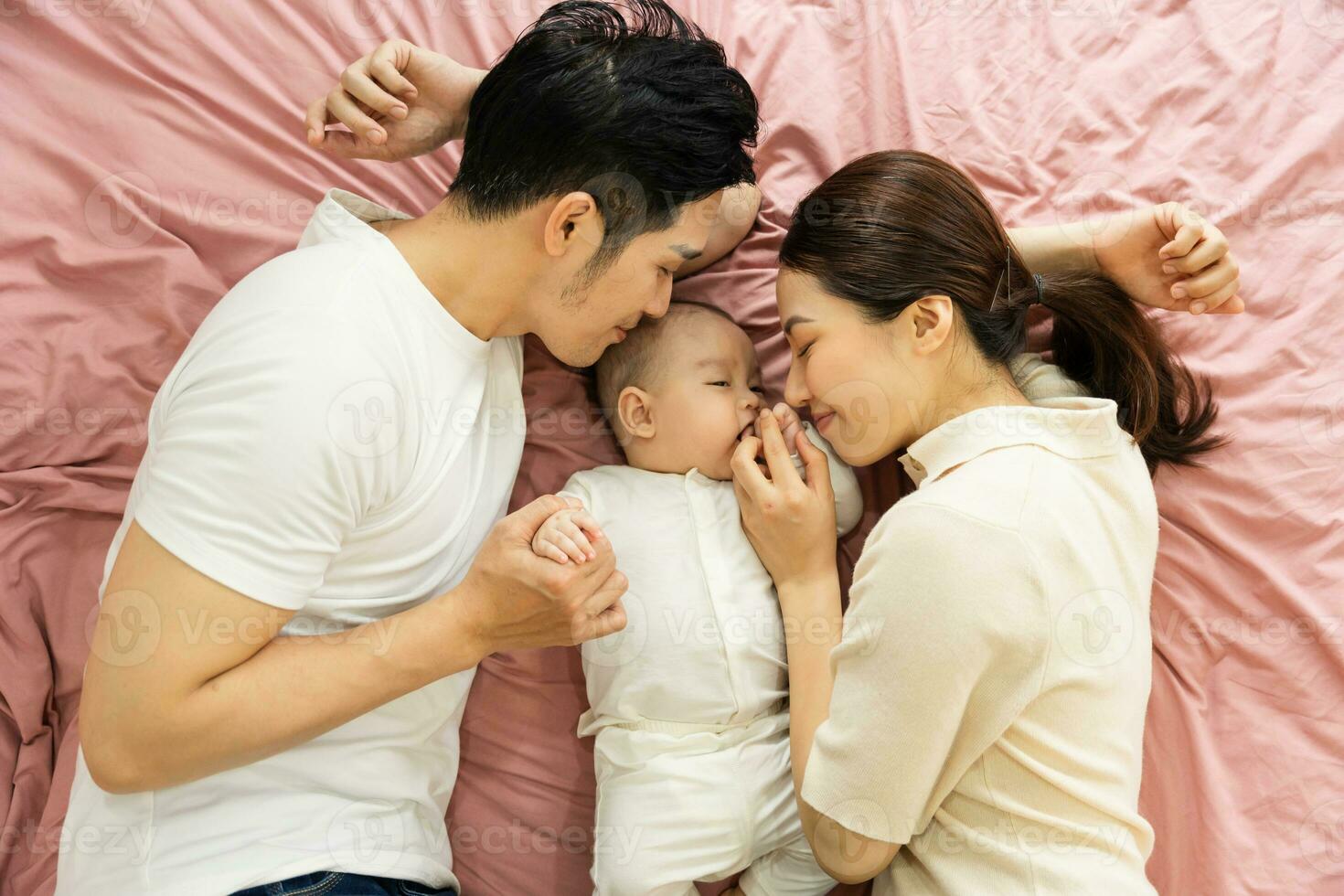 Asian family image with baby lying in bed photo