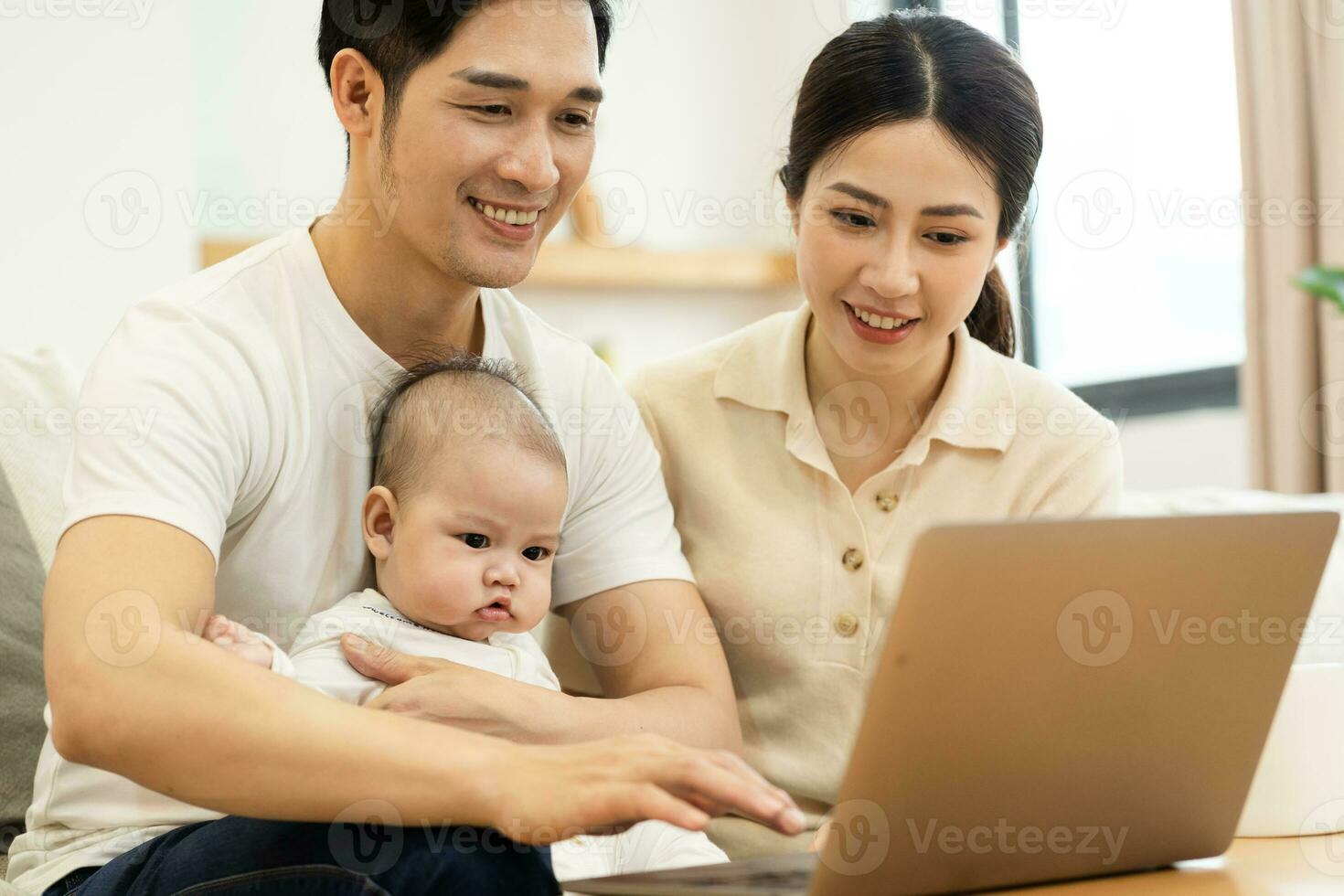 image of asian family with baby sitting on sofa using laptop photo