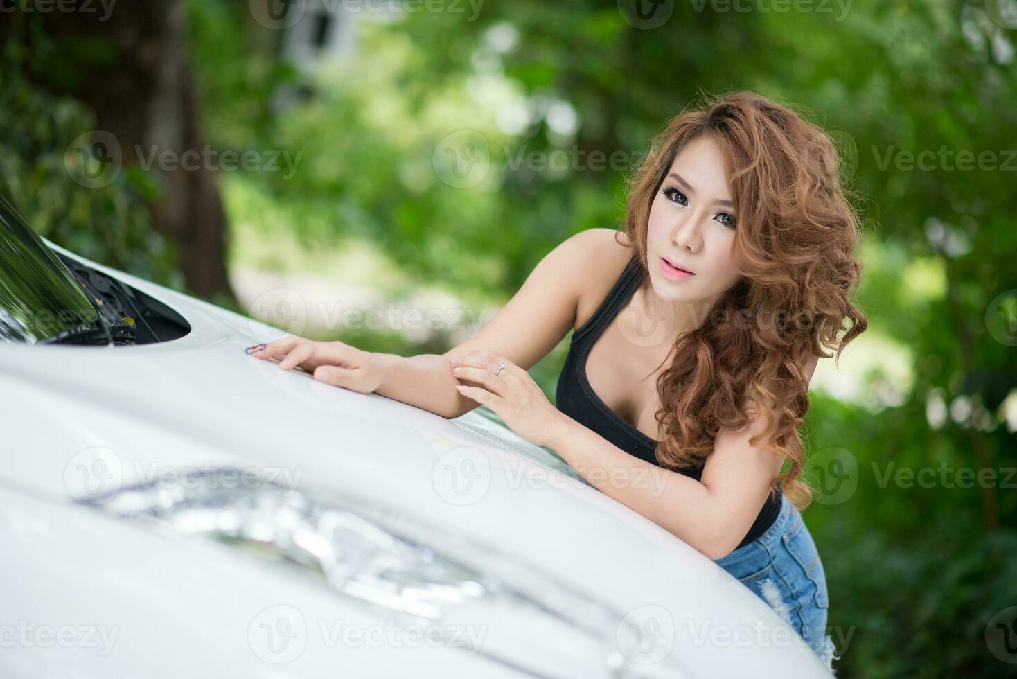 Sexy girl in black vest is posing on hood car photo