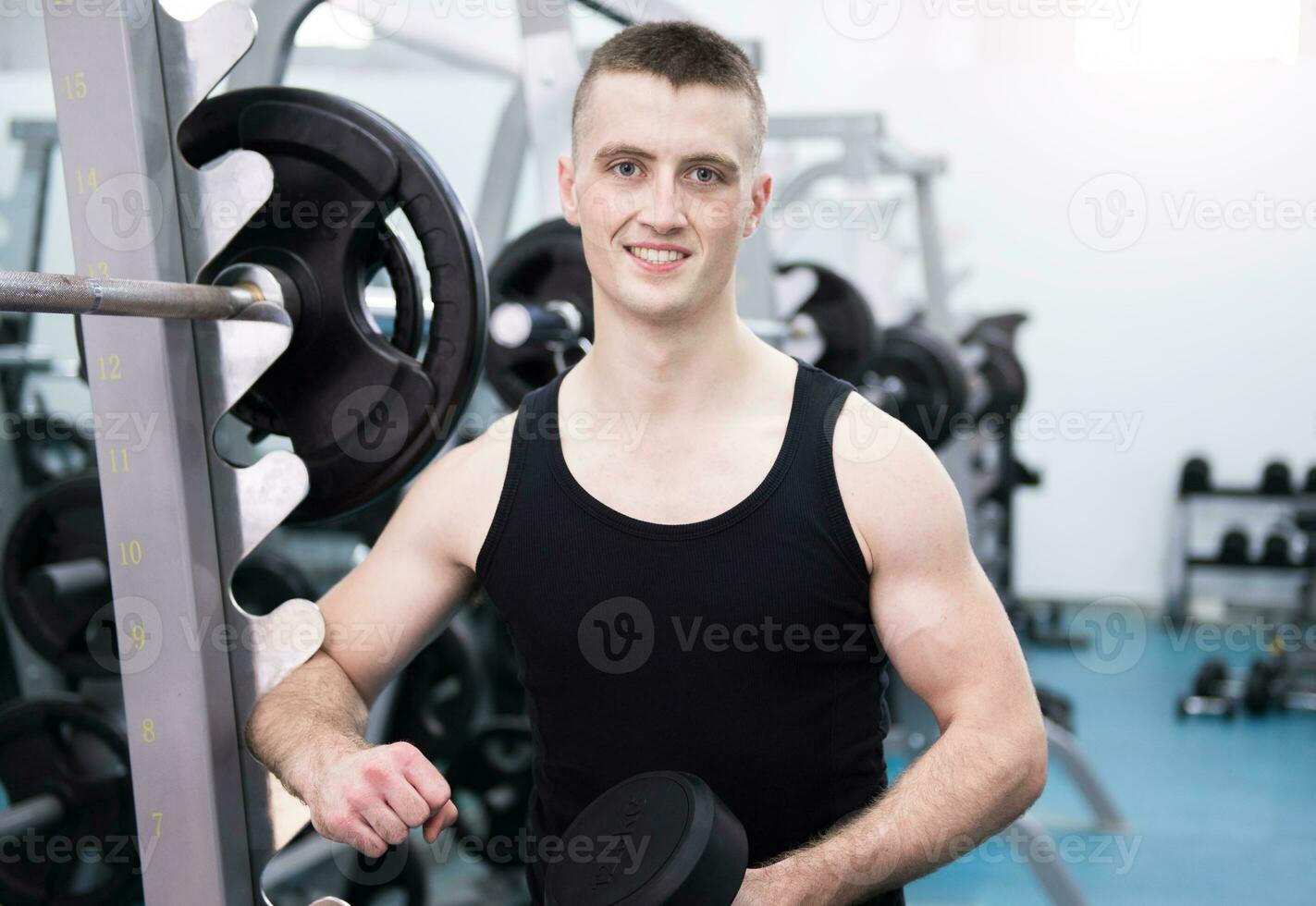 atlético hombre con un mancuernas en gimnasio foto
