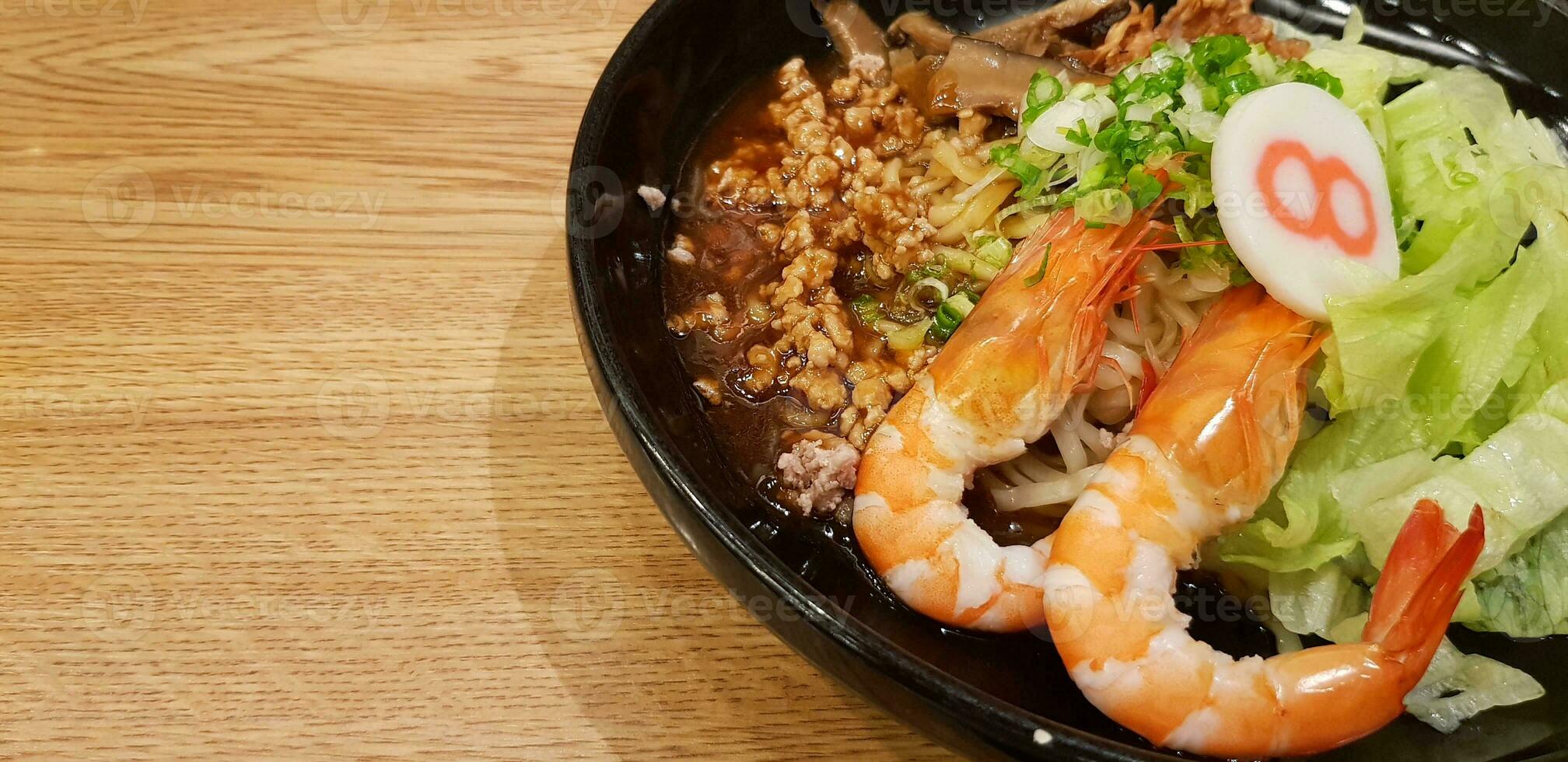 Kaisen ramen Noodle with prawn, fried squid, pork minced, Chinese mushroom in Kaisen sauce on wooden table with left copy space photo