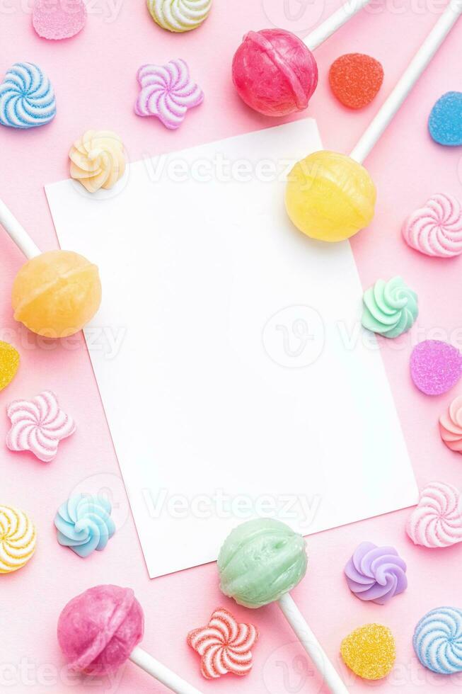 Sweet lollipops and candies and blank greeting card on pink background photo