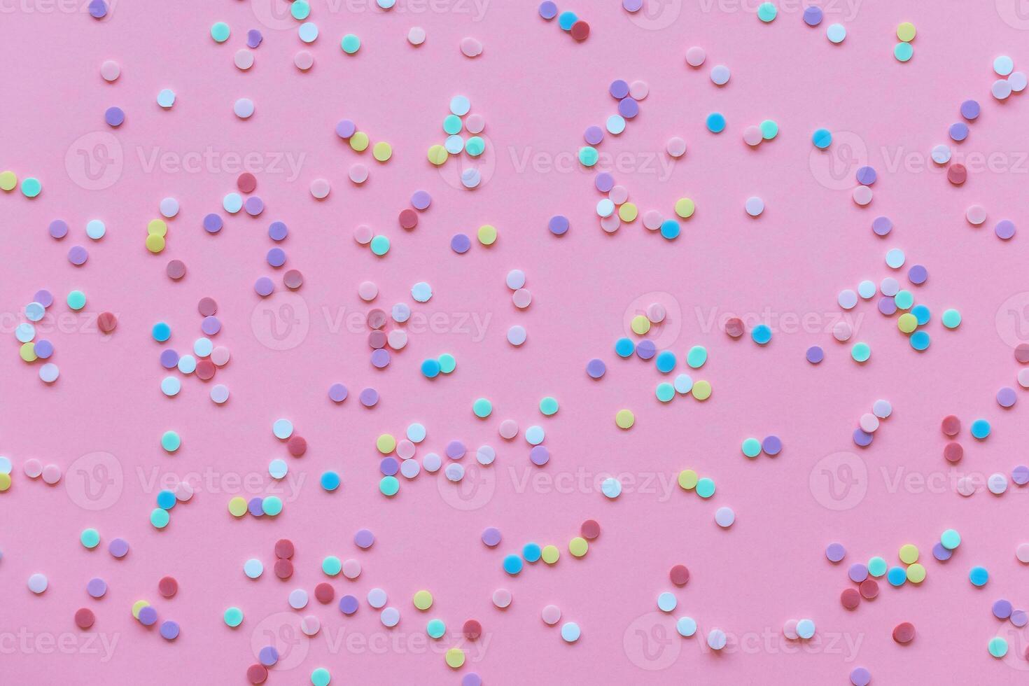 Plastic colorful confetti on a pink background photo