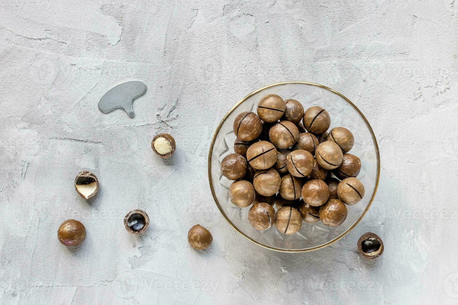 Macadamia nuts in shell in bowl on gray background photo