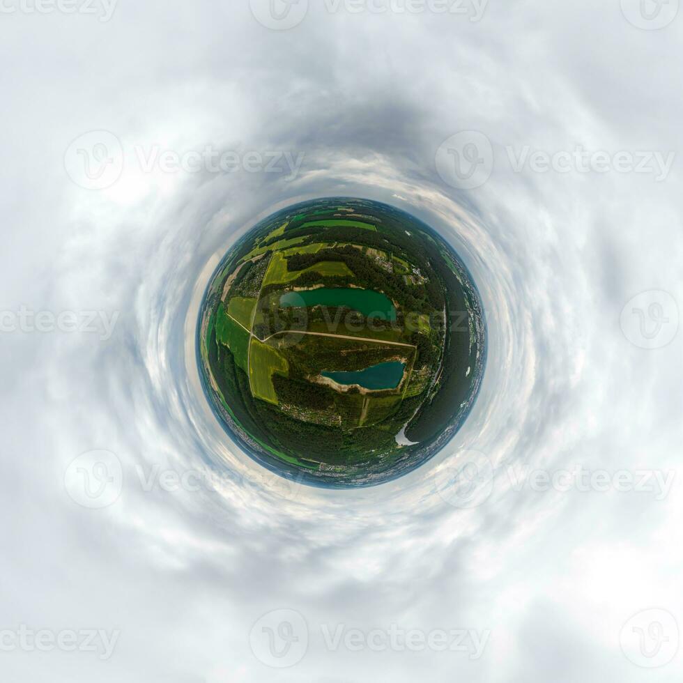 green tiny planet in blue overcast sky with beautiful clouds with transformation of spherical panorama 360 degrees. Spherical abstract aerial view. Curvature of space. photo