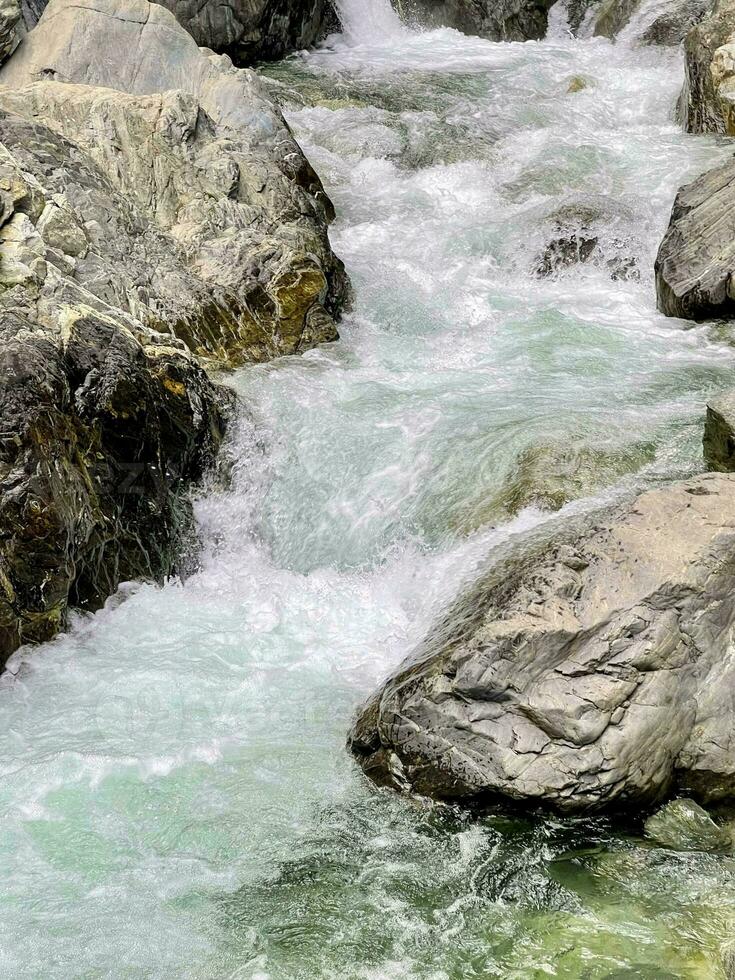 A stormy stream of a mountain river rushing among the stones photo