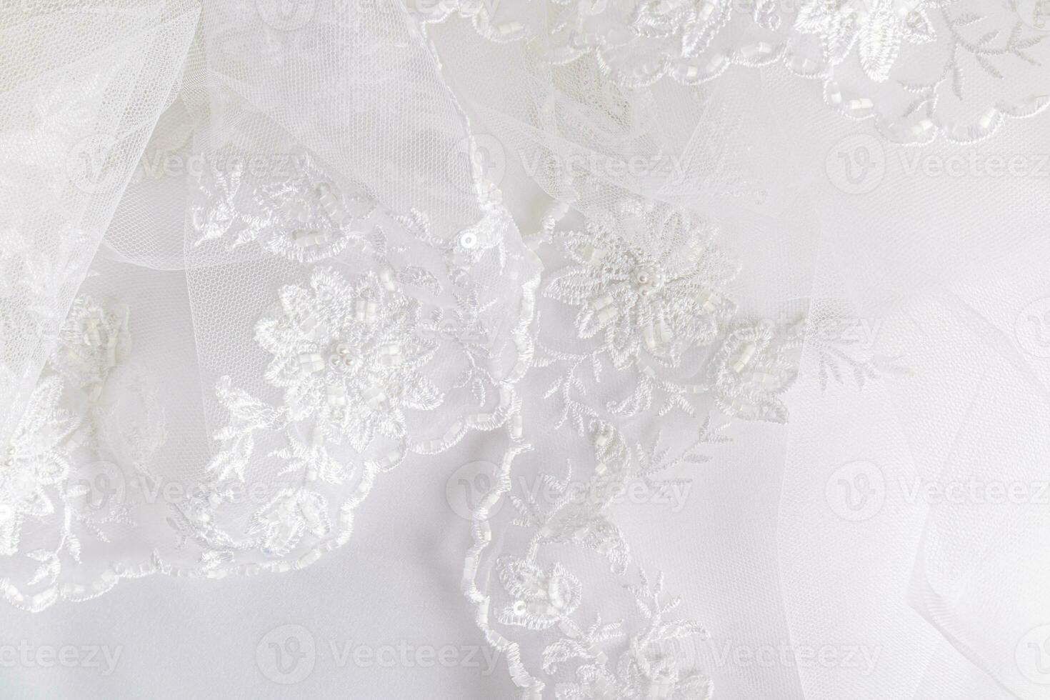 A chic openwork embroidered fragment of a wedding white veil with beads and pearls, with soft folds. Wedding background. photo