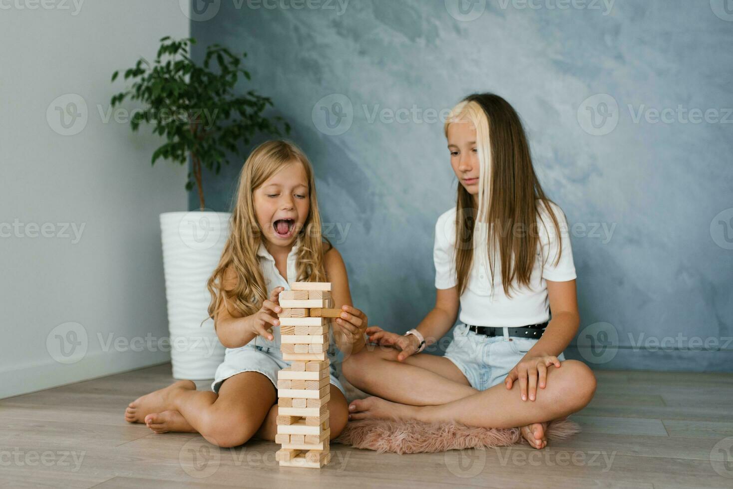 Sister girls are playing a board game of laying wooden blocks after school. Fun parties for kids, vacations at home photo