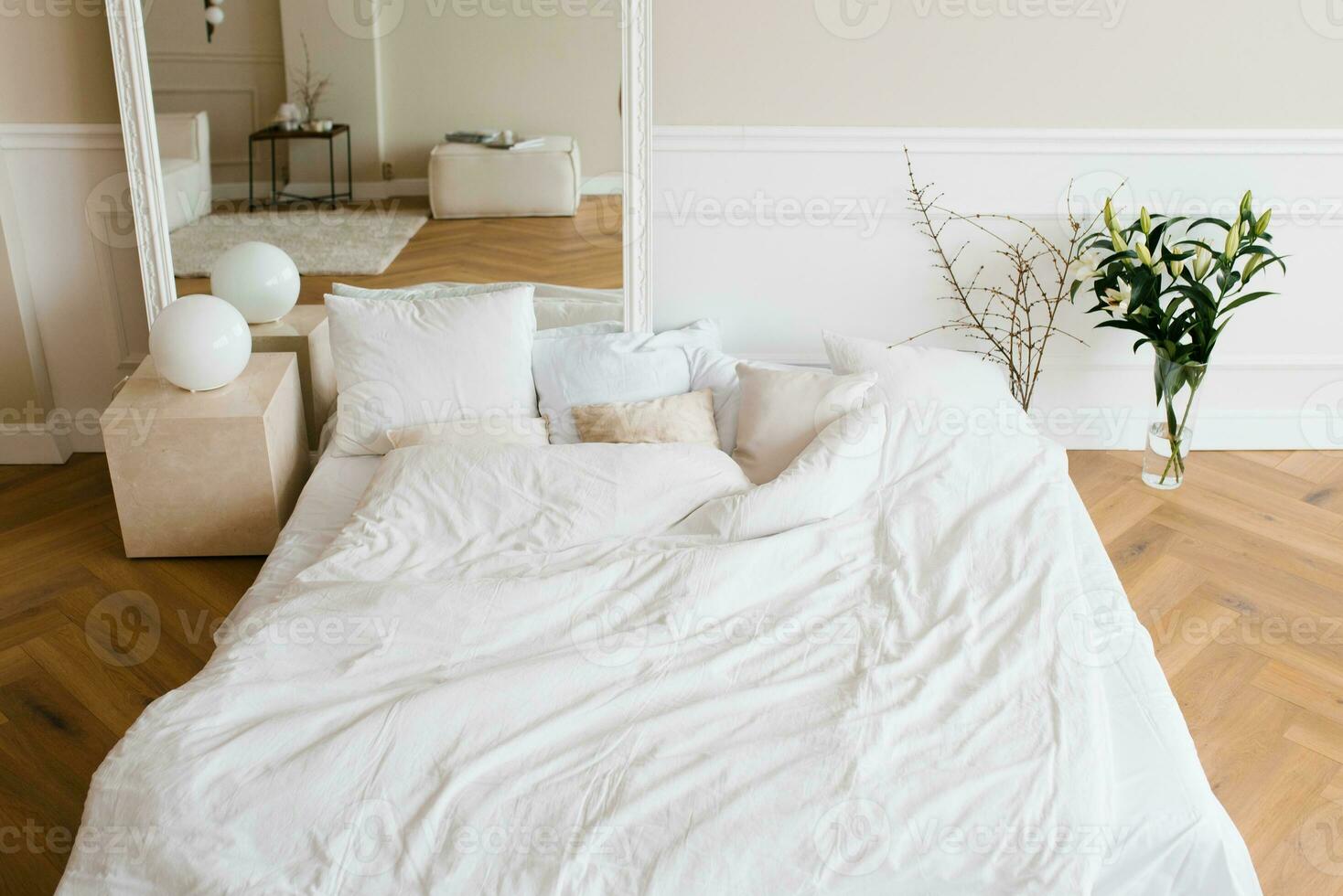 un doble cama con blanco ropa de cama y beige almohadas en un brillante escandinavo dormitorio, un cama en el piso y flores en un florero foto