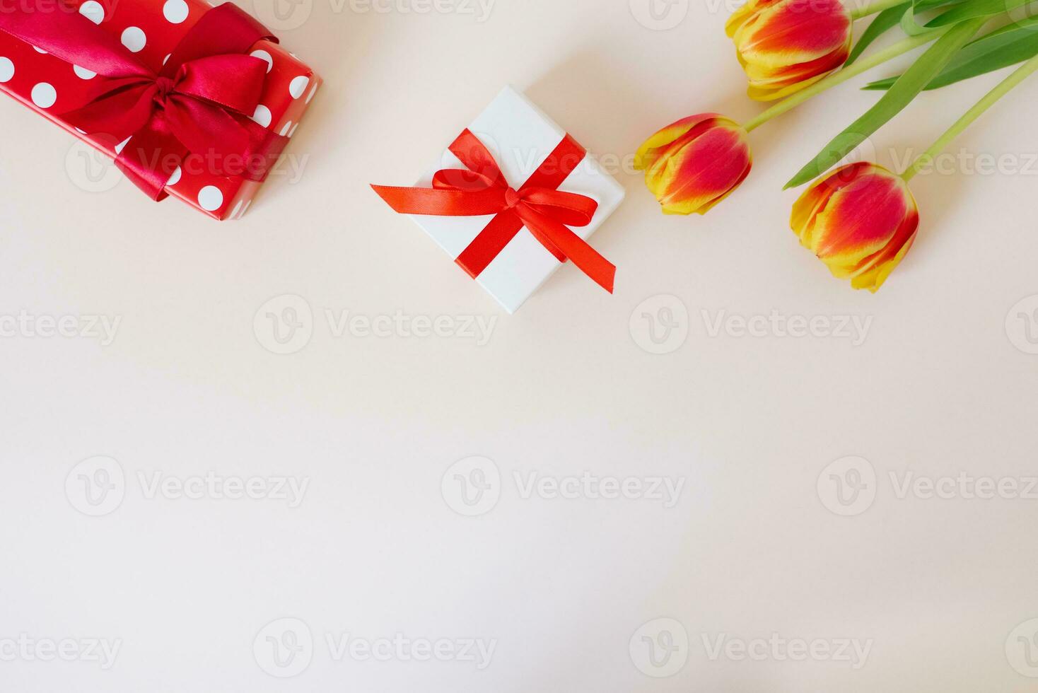 A bouquet of red spring flowers tulips and red gift boxes on white table with copy space. Valentine Day photo