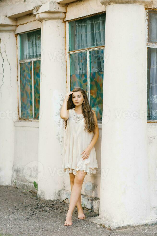 portrait of a beautiful girl in a summer dress with long hair, who holds her hand in her hair, straightening it photo