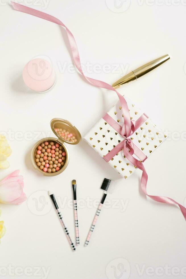 Pink and yellow flowers, tulips, a gift box with a bow, accessories and cosmetics. The layout of a female desktop in a home office. Flat layout, top view, blog title background. photo