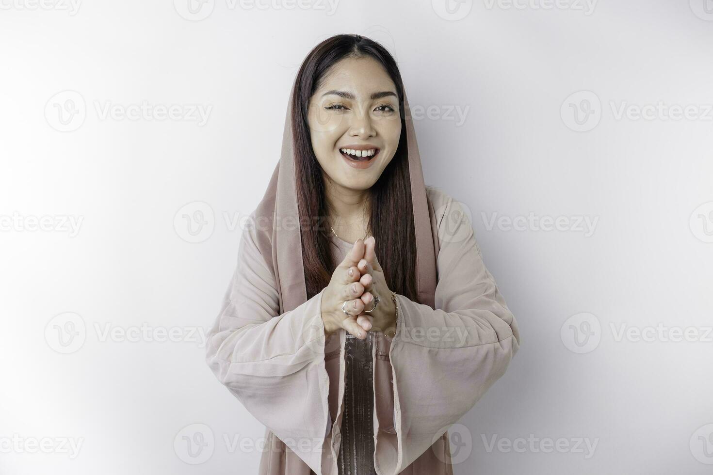 Portrait of a young beautiful Asian Muslim woman wearing a headscarf gesturing Eid Mubarak greeting photo