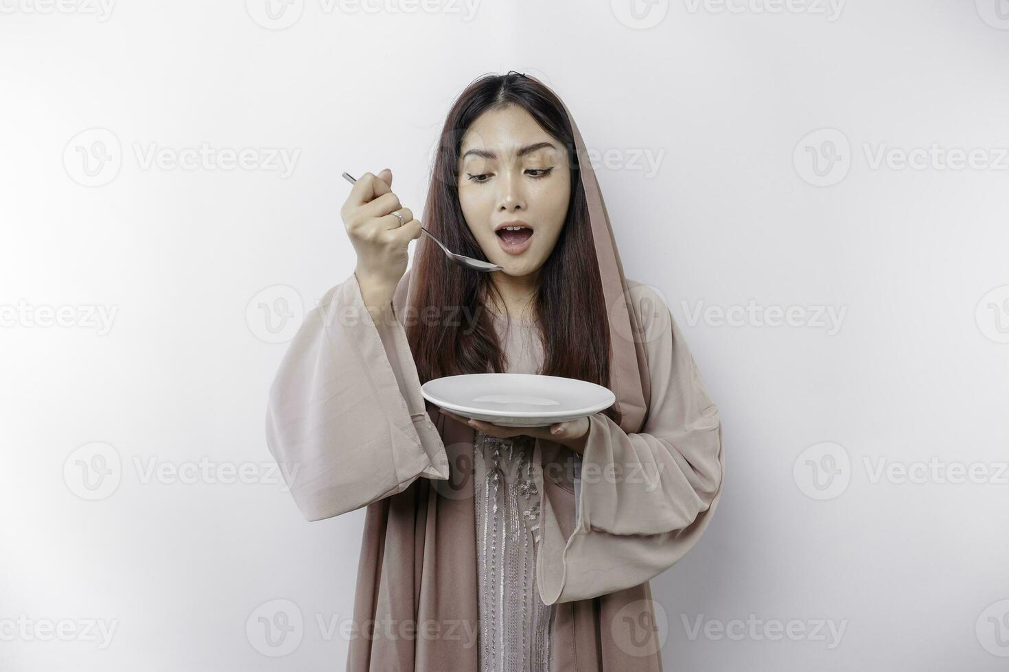un sonriente asiático musulmán mujer es rápido y hambriento y participación y señalando a un plato foto