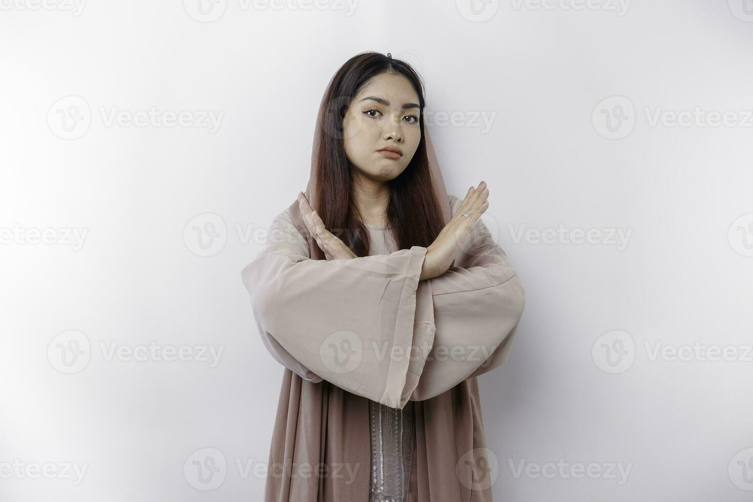 Beautiful Asian Muslim woman wearing a hijab with hand gesture pose rejection or prohibition with copy space photo