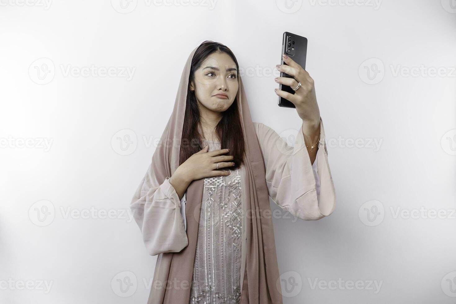 un infeliz asiático musulmán mujer vistiendo un Pañuelo es limpiando su lágrimas en desesperación durante vídeo llamada foto