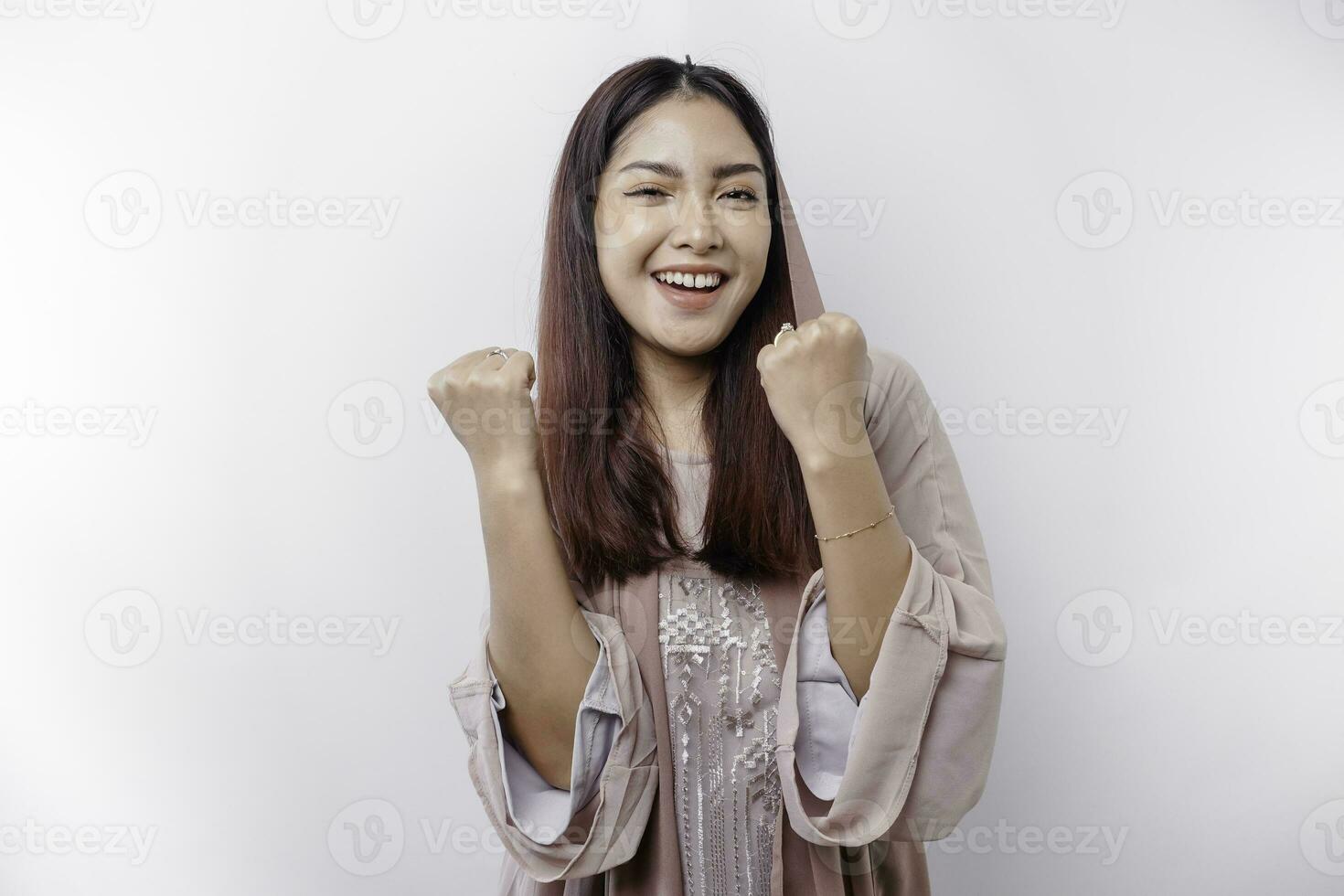 A young Asian Muslim woman with a happy successful expression wearing a hijab isolated by white background photo