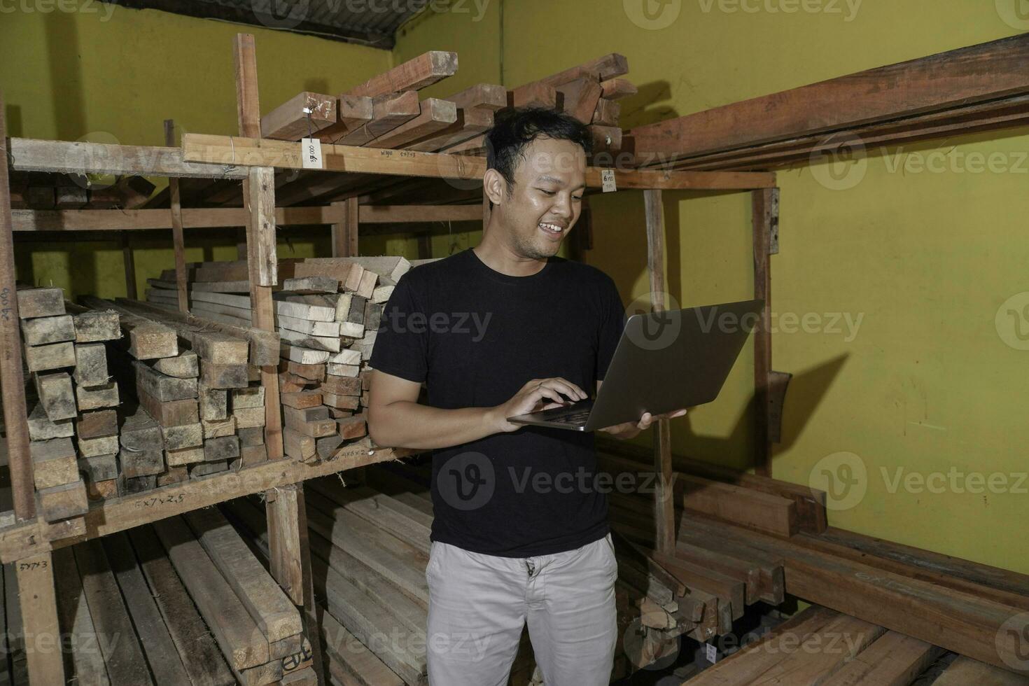 hermoso asiático hombre es sonriente mientras comprobación su carpintería taller foto