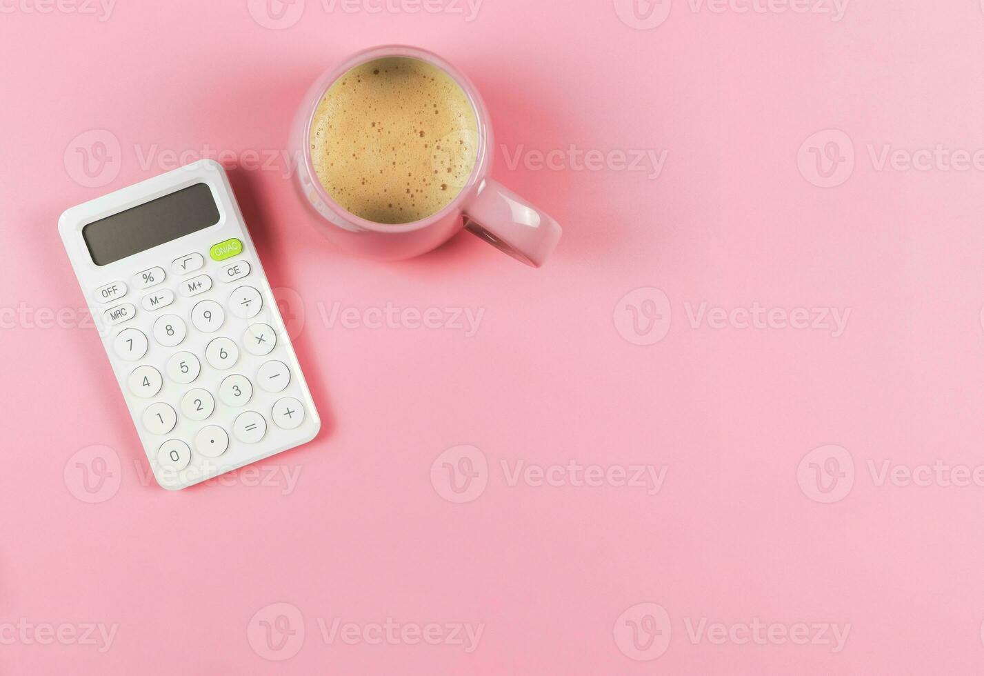 flat lay of white  calculator and pink cup of coffee on pink background with copy space. photo