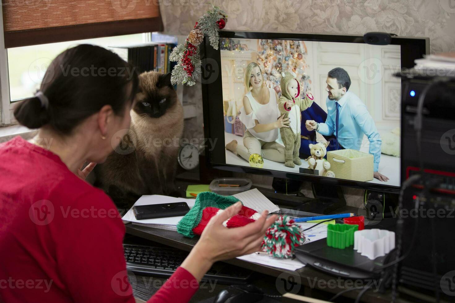 A woman is sitting at a table and talking via video link with relatives at the holiday. Staying at home, quarantine and social distancing during the New Years. photo