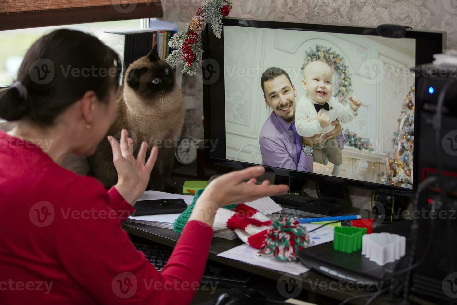A woman is sitting at a table and talking via video link with relatives at the holiday. Staying at home, quarantine and social distancing during the New Years. photo