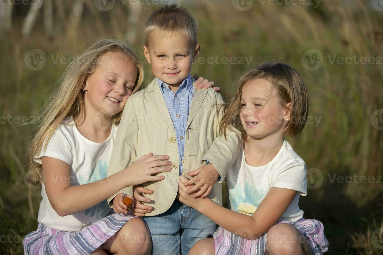 Happy family sisters and little brother on a summer meadow. photo