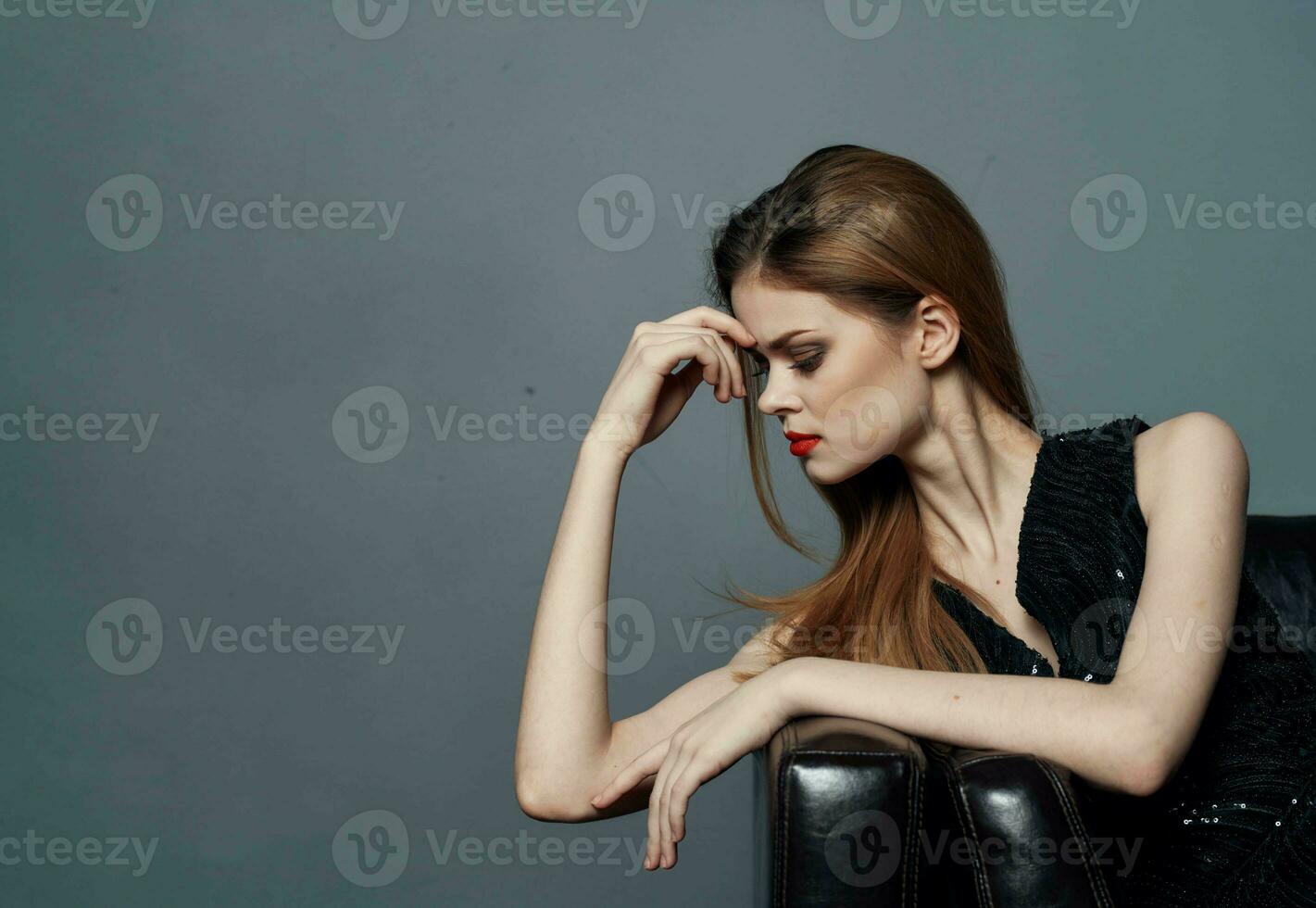 retrato de un elegante mujer en negro vestir noche maquillaje y rojo labios gris antecedentes foto