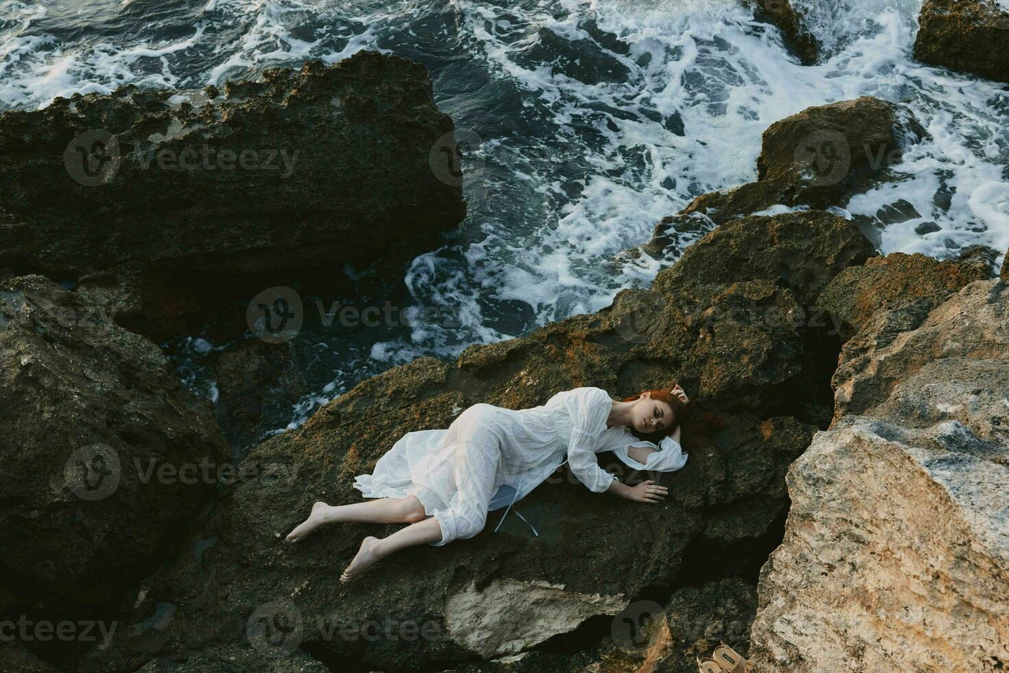 mujer en un blanco vestir acostado en un Roca en un blanco vestir verano vacaciones concepto foto