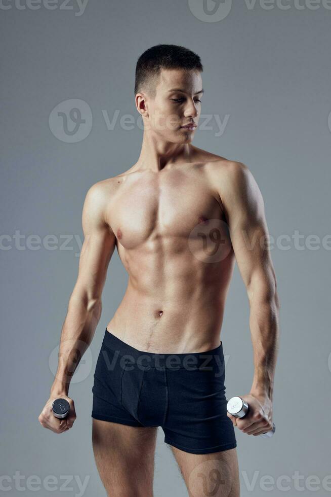 sporty man in black shorts with dumbbells in hands pumped up body posing exercise photo