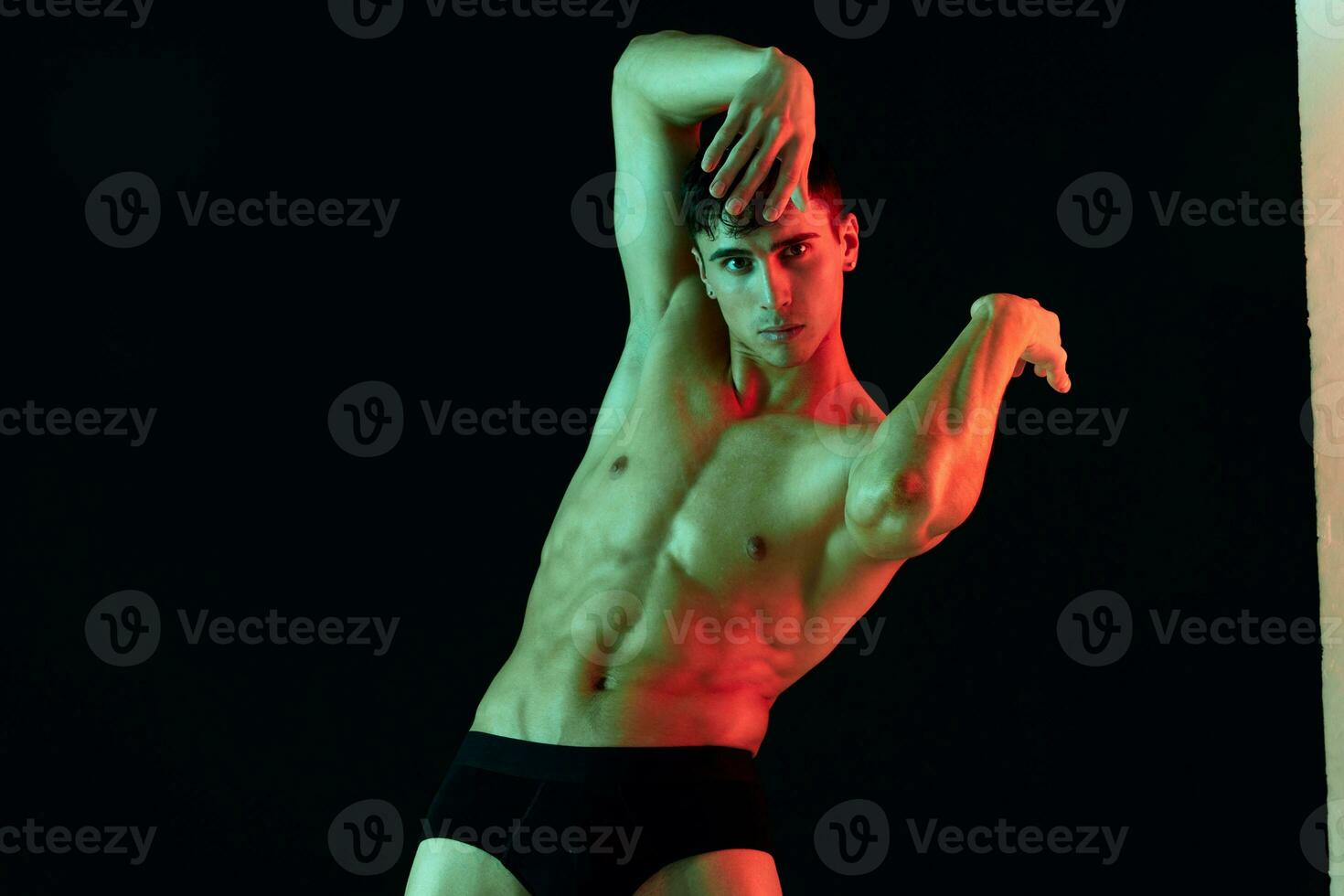 bodybuilder holds hand behind head on black background neon light fitness photo