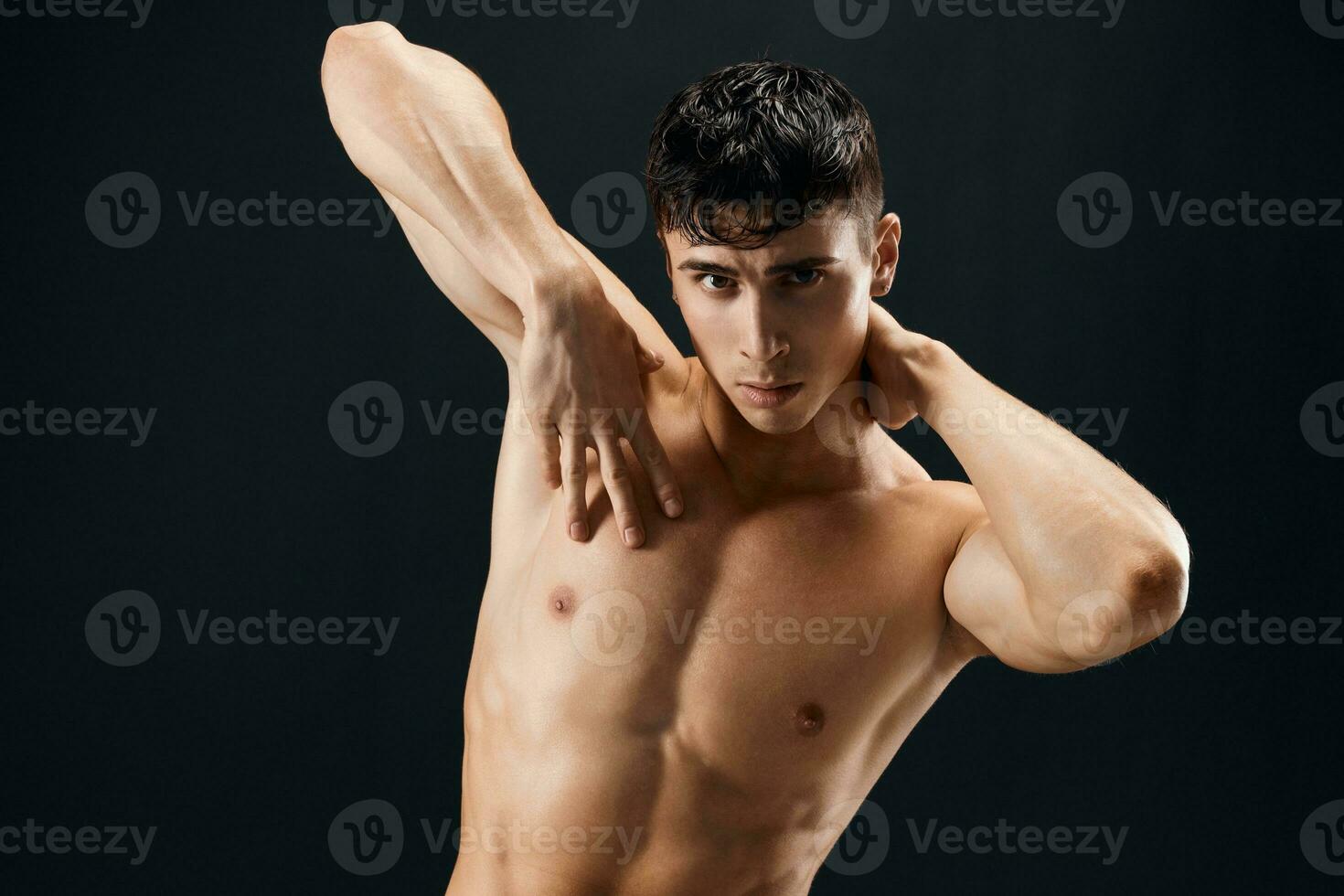 sporty man with muscular muscle body posing against dark background cropped view photo