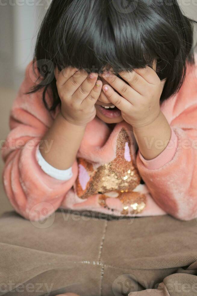 a upset child girl cover her face with hand photo