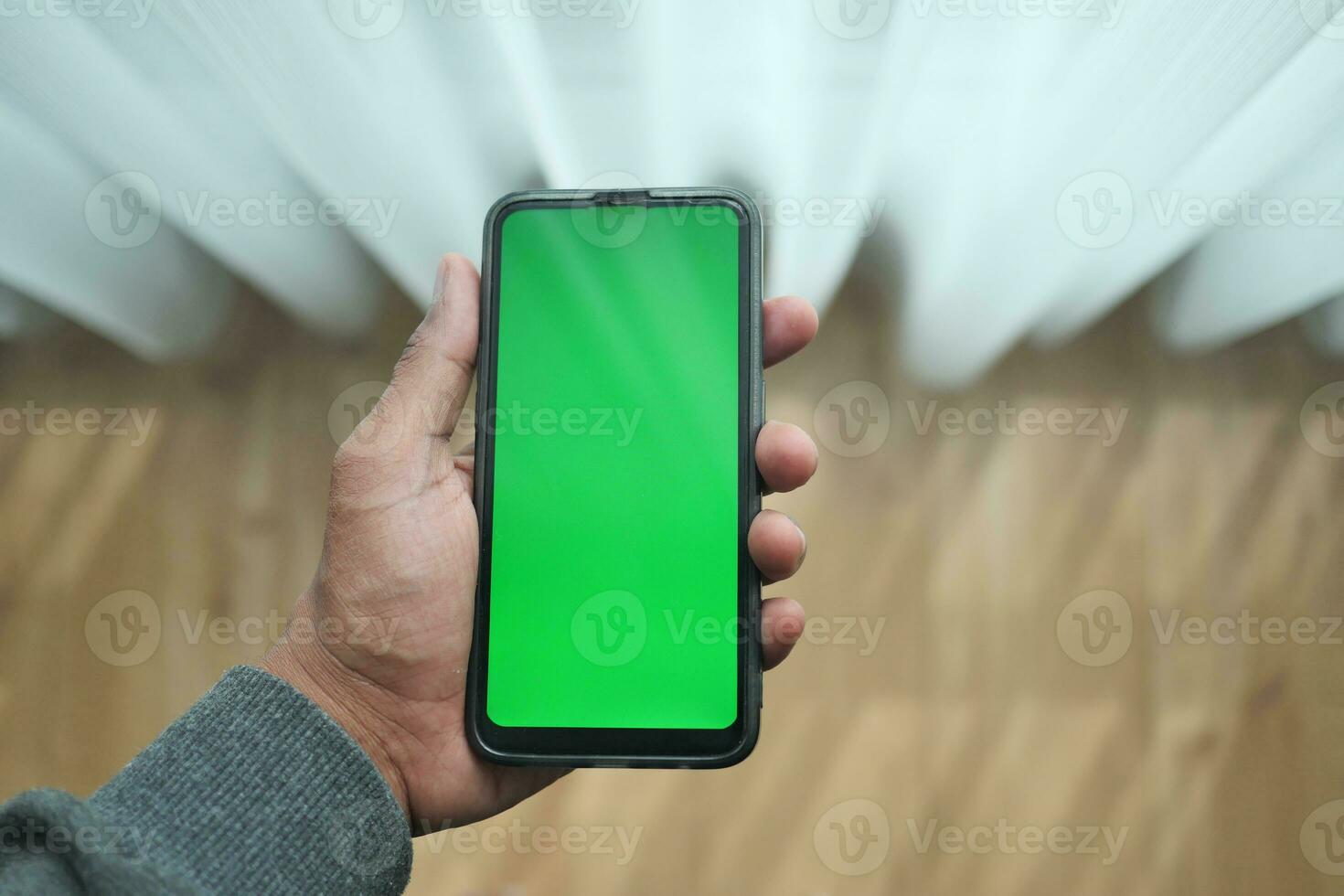 POV shot of young man hand holding smart phone at home photo