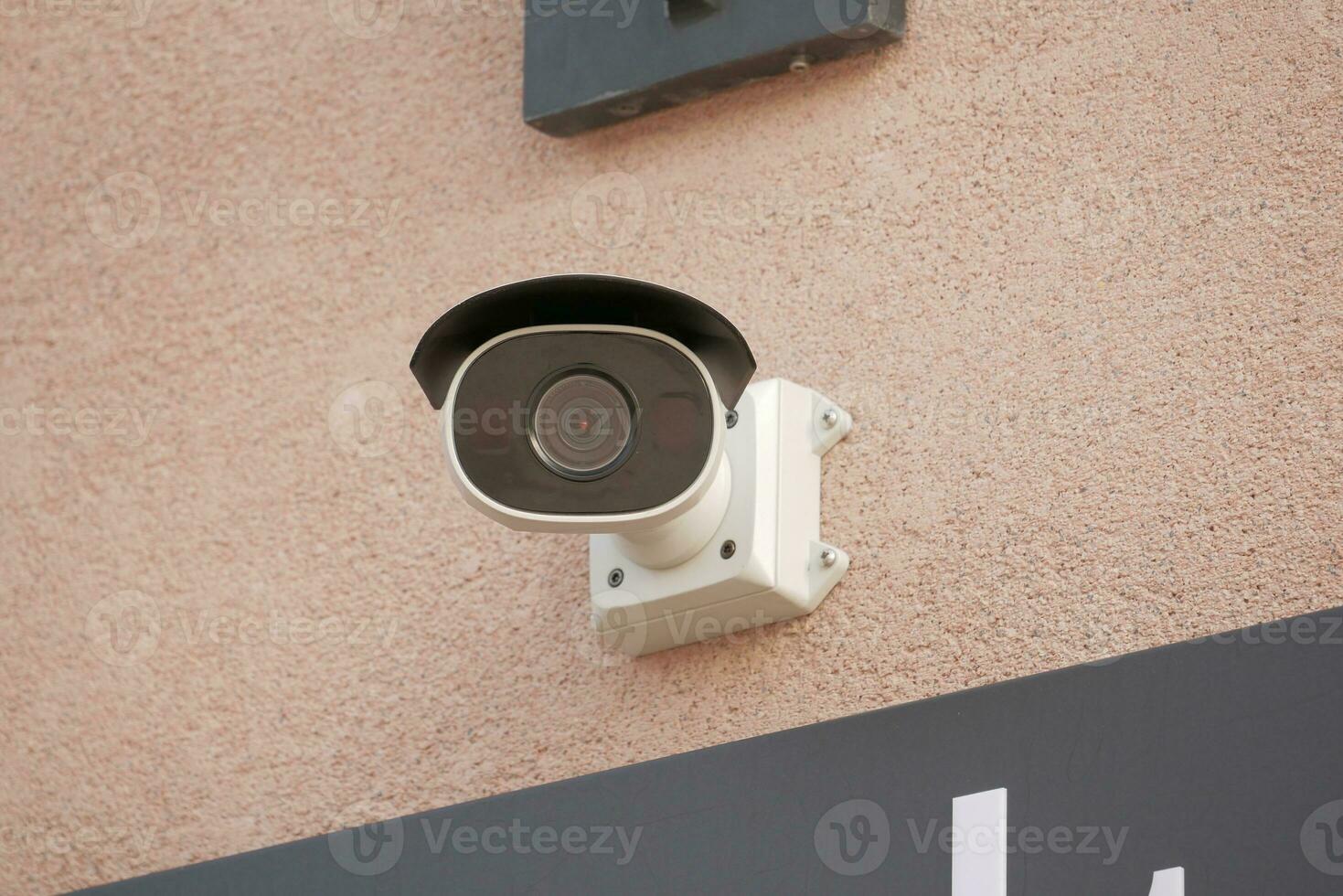 CCTV security camera operating on wall photo