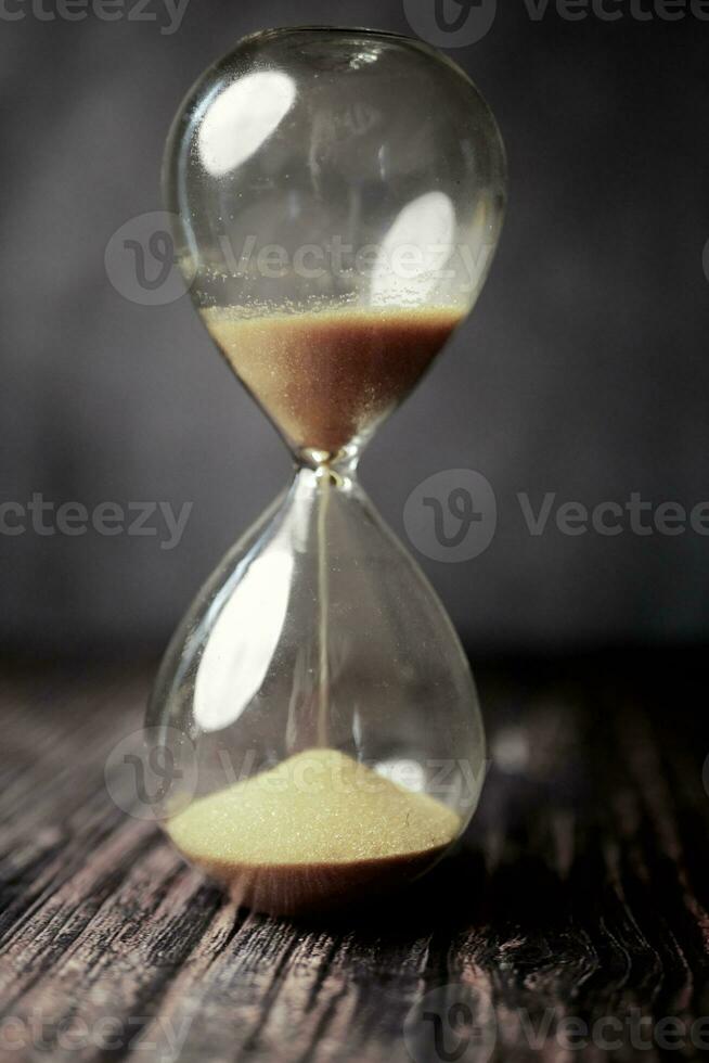 hourglass on table, sand flowing through the bulb of sandglass photo